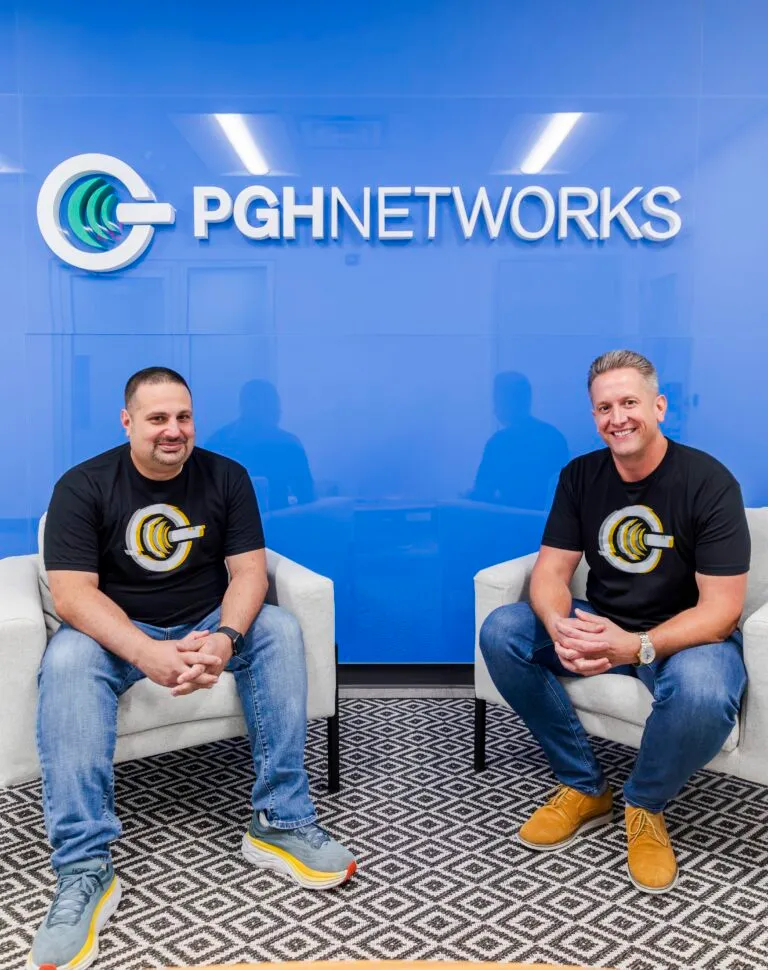 Greg Pack and Bill Weisser, owners of PGH Networks, in front of the PGH Networks logo